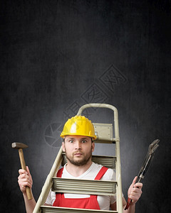 一种红色的管道手持梯子锤和铁棍的笨手工人与具脚人的肖像图片