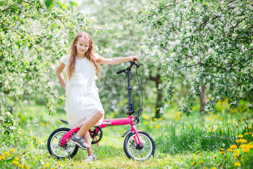 可爱的女孩在美丽夏日户外在盛开的公园里骑自行车可爱的女孩在美丽夏日户外骑自行车术快乐的叶子图片