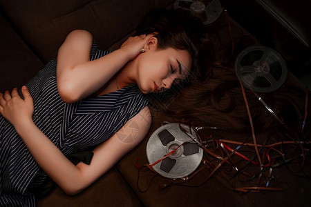 老的一个穿蓝条纹衣服的亚洲年轻女孩肖像躺在沙发旁边的上带磁玩线圈图片
