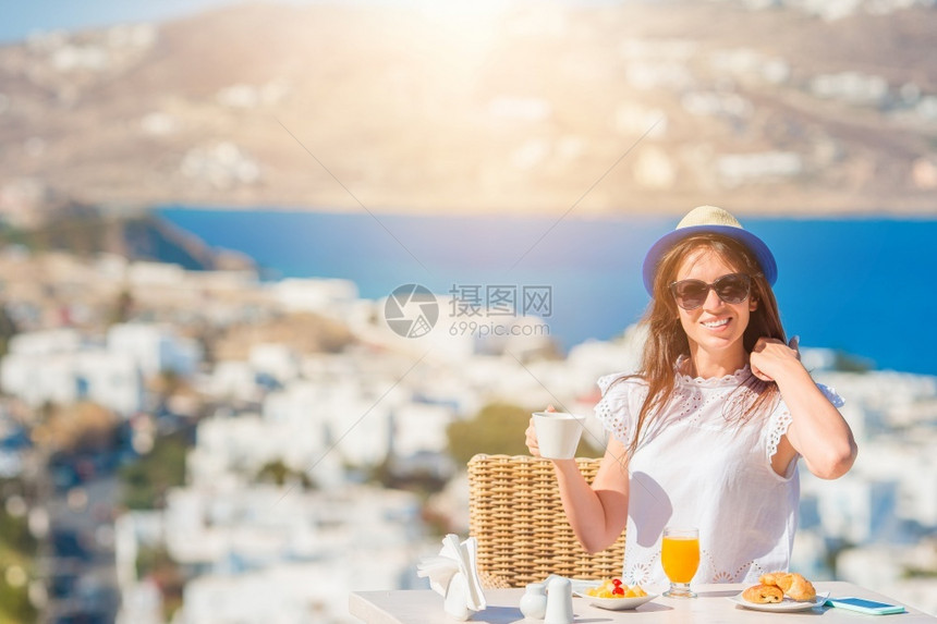 美女在户外咖啡厅吃早饭风景令人惊艳女孩清晨享受热咖啡美丽的女士在户外咖啡厅吃早餐风景令人惊叹海热的希腊图片