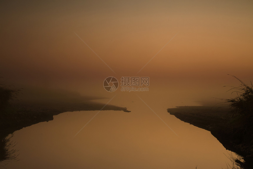 季节水平的非常浓厚雾以红色亮出太阳漂浮在湖上美丽的颜色在一个微妙的红色黄图像令人感兴趣的明信片与复制的空间蒙图片