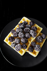 黑底带冰冻莓的比利时饼黑莓带紧闭的比利时华夫饼焦糖香脆的小吃图片