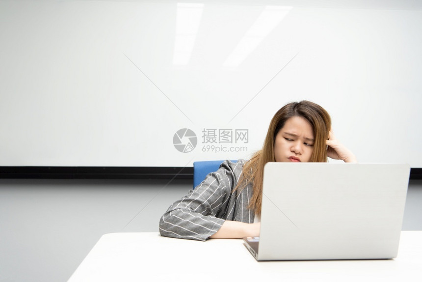 松弛赢亚洲女是学生商业女以计算机笔记本工作在办公室会议用笔记本电脑工作有白板背景思考的办公会议室用笔记本电脑工作将情感集中到概念图片