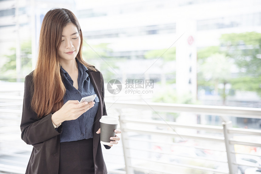 现代的使用智能手机在线购物打电话发短信互联网技术生活方式的女商人使用手机在城市街道上行走智能手机自信女现代城市套装在线的图片