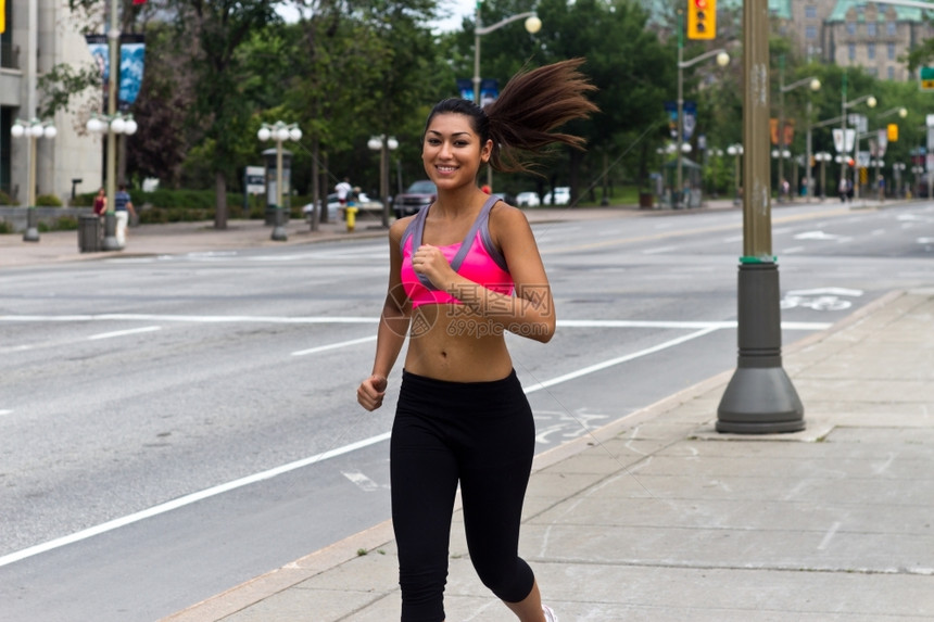 年轻的20多岁合适的年轻女子在繁忙的街道上奔跑锻炼图片