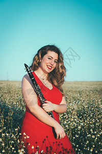 音乐家穿着红裙子的女人在田里玩着单簧管风白种人图片