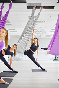 Fly瑜伽班女团体培训挂吊床上的合身装饰小费和舞蹈锻炼混合了在体育室Fly瑜伽课上做运动的妇女挂吊着床绞刑有氧冥想图片