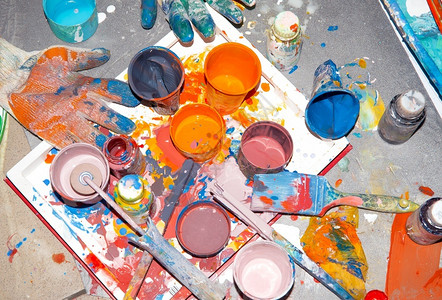 油漆木制的艺术家不同罐头和杯子中混合的多彩涂料绘画员配额工具在不同罐子和杯中混合的刷乌紫色涂料画家配额工具背景图片