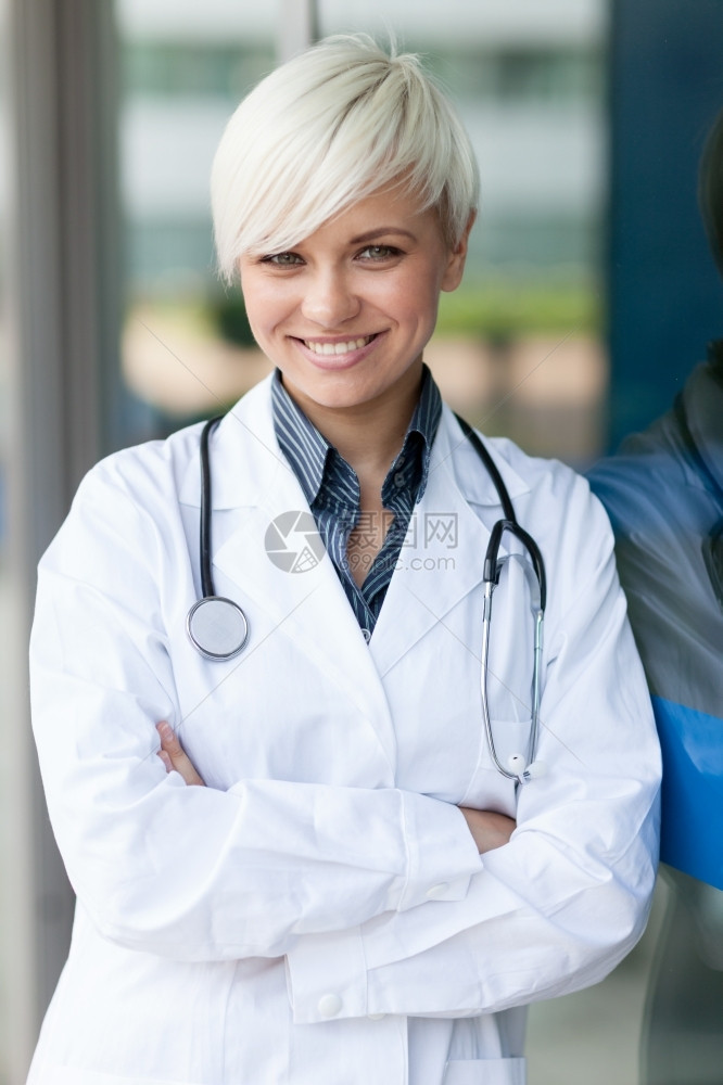 成功的吸引人在玻璃墙前微笑着的有魅力女医生制服图片