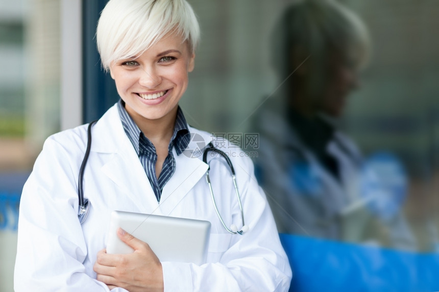 办公室制服在玻璃墙前微笑着的有魅力女医生金发图片