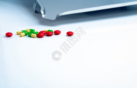 红圆制糖涂层药片和绿色黄柳胶囊白桌上有不锈钢药品托盘剂学概念制业用产品保健和药物白色的工业医疗背景图片
