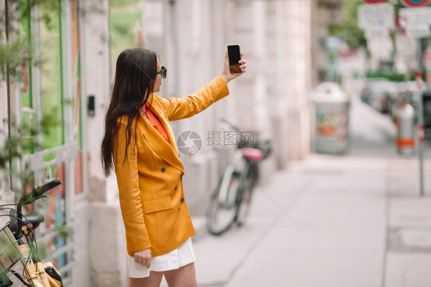维也纳市外的年轻有吸引力旅游者在意大利市外的年轻有吸引力旅游者在意大利城外的旅游者中由她的智能手机在城市里聊天电话年轻的时尚图片