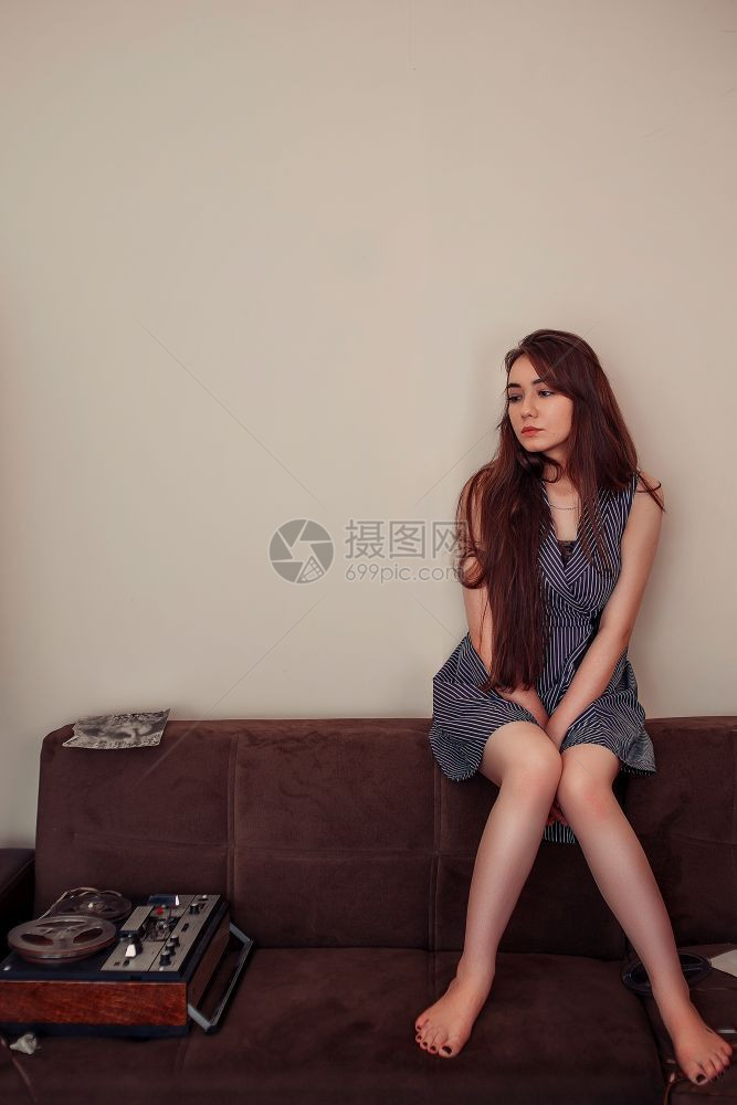 音乐一个穿蓝条纹衣服的亚洲年轻女孩坐在沙发上旁边有磁带和老式录音机经典的数据图片