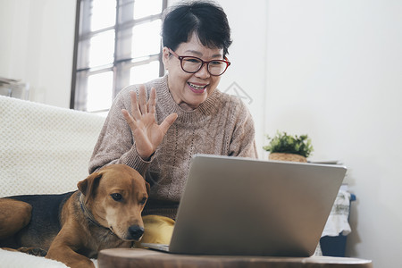 老的亚洲高龄女在笔记本电脑上进行视频呼叫在屏幕上挥手与远距离人士在网上聊天请享用在线的背景图片