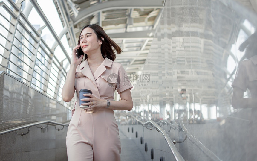 早上班时身着正式粉红西装的亚洲商业妇女拿着平板和咖啡杯到外面去工作早晨粉色的工作场所图片