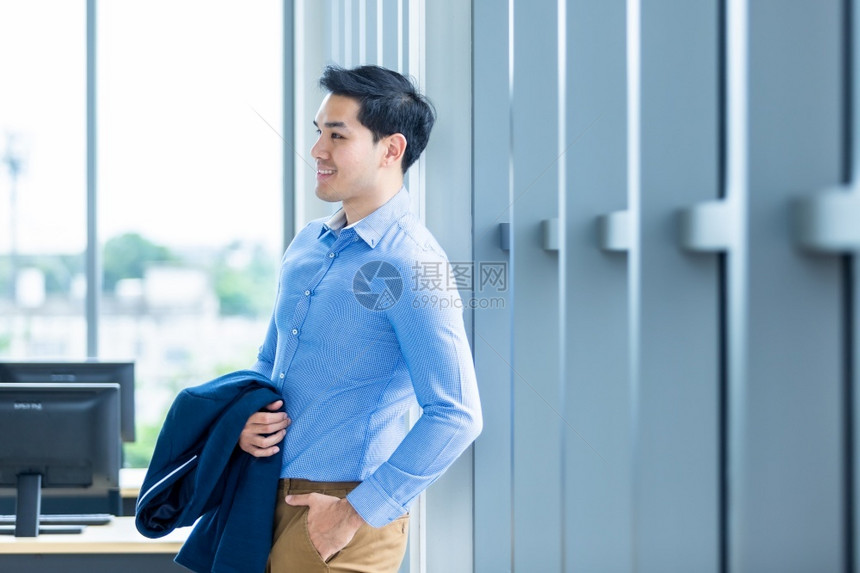 英俊的商业成熟一个快乐功的感觉肖像赢者英俊年轻的亚洲青商人穿着一件蓝外套的人商服和在窗户上的蓝衬衫在办公室背景里图片