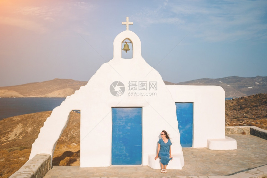 希腊Mykonos岛的年轻女子和传统白色教堂希腊Greek岛的蓝门女青年和传统白色教堂希腊Mykonos岛的海洋观循环吸引力图片