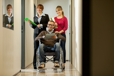 商人和他的同事在走廊上坐轮椅的商人们白种自信的一体化图片