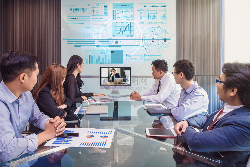专业的通过在现代会议室显示监视器与经理举行像会议商业人员概念的Asian商业团队小组通过在现代会议室显示器与其经理举行电视会议技图片