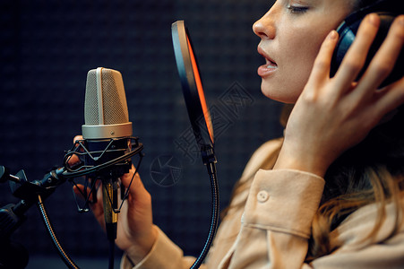 生产播送耳语女演员在麦克风上唱一首歌录音室内地记背景专业语音记录乐工作场所创造过程现代音频技术等背景工作室内演唱麦克风和录音室的背景图片