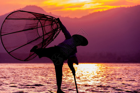 自然日落时的渔夫剪影茵莱湖日落时的渔夫剪影缅甸技术波纹图片