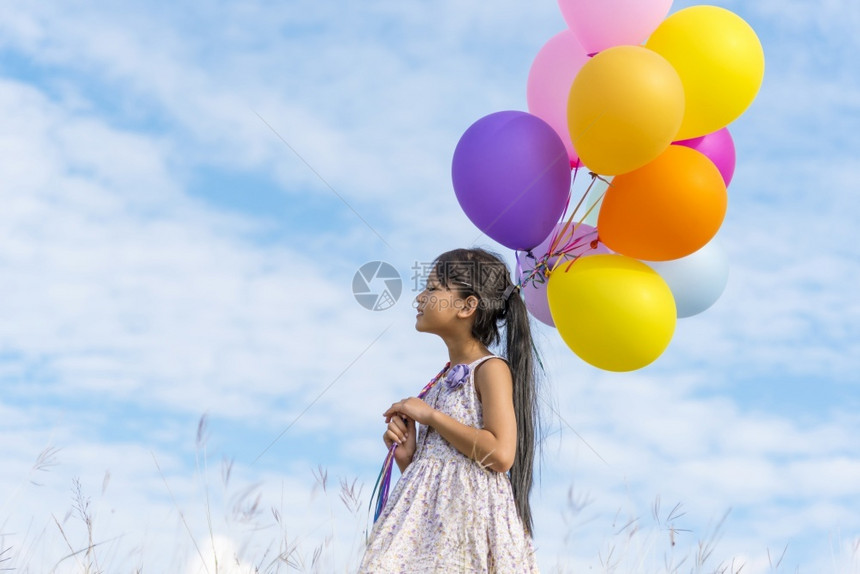 束人类快乐的可爱女孩拿着气球在绿色草地白云和蓝天空上运行快乐的天空手拿着充满活力的空气球在生日派对上玩欢乐的可爱女孩自由图片