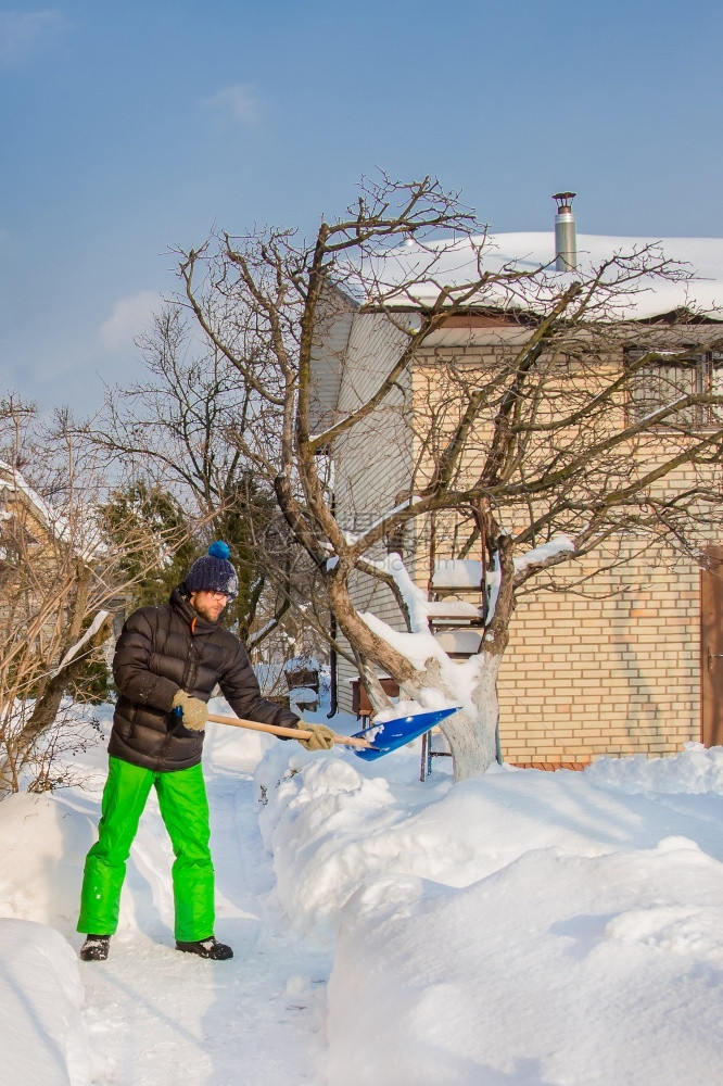 户外小路一个人清理他家附近的院子和雪花园一个阳光明媚的冬日天气晴朗一个男人清理他雪屋附近的院子一个阳光灿烂的冬季天晴图片