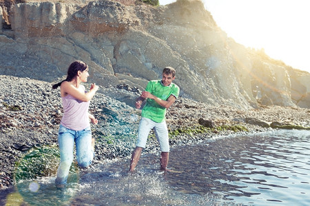 情人在海滩上玩水的情侣喷花太阳光束和镜头照明弹运动模糊夏令人们图片
