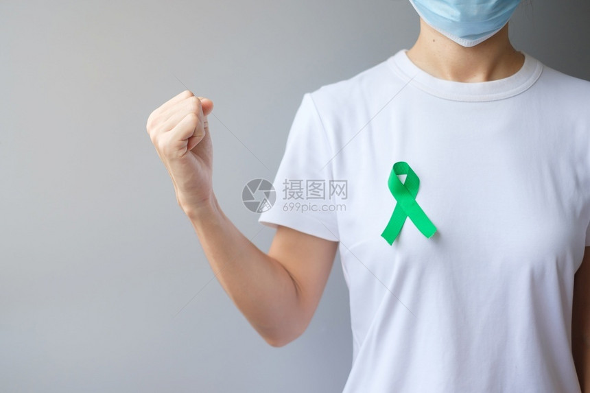 手拿绿色丝带预防癌症概念图片