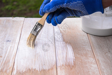 男人在白色油漆表面上涂色板给木漆色保护的建造持图片