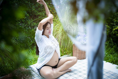 期待孕妇在户外做瑜伽和手臂扎紧放松和保健概念的孕妇分娩帐篷图片