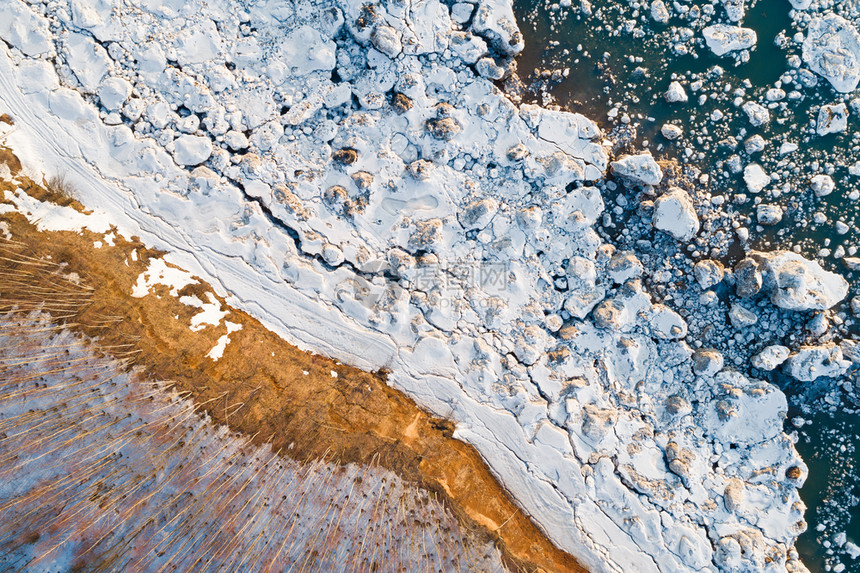 美丽湖岸的顶端风景湖面上露着树木雪石和水中的冰追踪排图片