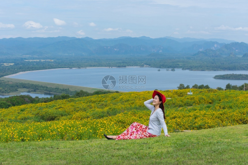 身着自然花的美丽女子她穿着白色礼服和红帽子在泰国兰芒省MaeMohCoalMine的TungBuaTong墨西哥向日葵田上穿白裙图片