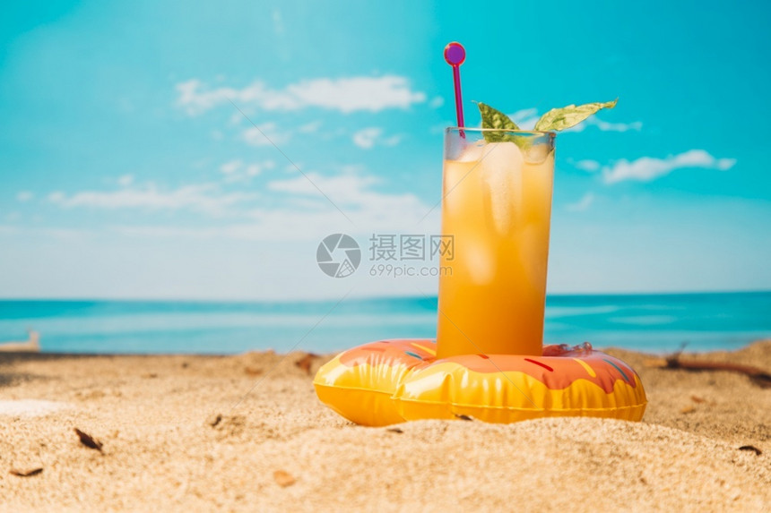 沙滩上的橙汁饮料图片