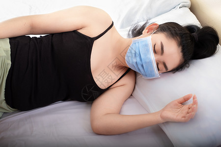 戴口罩躺在床上生病的女士图片