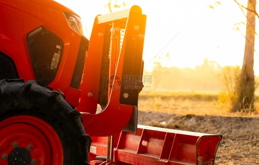 胎夏季上午停在水稻农场的橙色拖拉机夏晨停在稻田阳光照农业场中的机械智能作概念场中的机动车辆农场中劳动储蓄机械种植园用设备犁图片