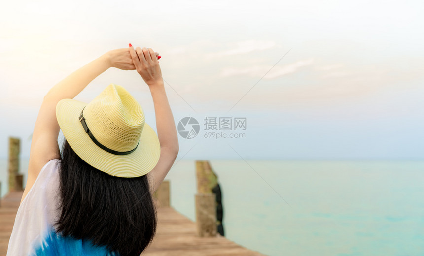 木制的岛欢乐亚洲年轻女在临时装风格草帽放松和享受热带天堂海滩节假日的回观女孩在暑假的时候坐度胜地的木头码上海洋图片