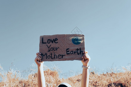 保护地球海报活动家种植园在蓝天气候变化概念的背景下手举拿着标语海报爱你的地球母亲爱你地球母亲横幅背景