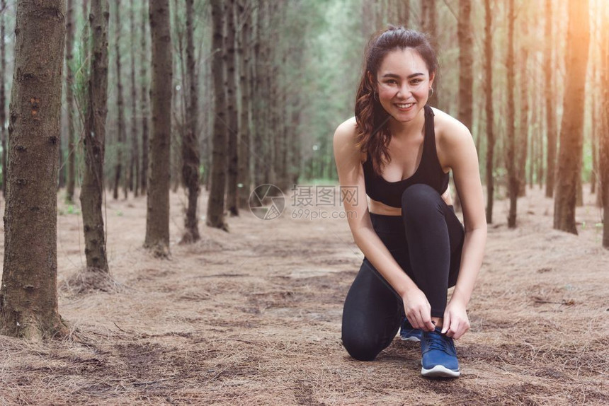 女训练人在森林里慢跑时绑起鞋带着饮用水瓶回到森林边上妇女们用自来水瓶把人和生活方式概念捆绑在一起保健和福利主题公园和户外主题绳索图片