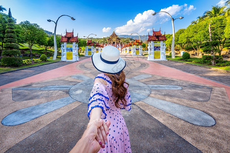 著名的花园拉查普鲁克女观光客手握着芒尔斯柯的手并带领他到泰国清迈市皇家花旗大教堂RoyalFloraratchaphruek北塔背景