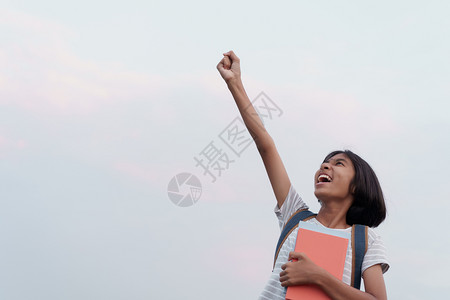 同时提高浓度旅行亚洲女学生成功快乐面露兴奋同时在夏天早上拿着一本手举起的书到蓝天背景夏日清晨愉快瞳孔背景