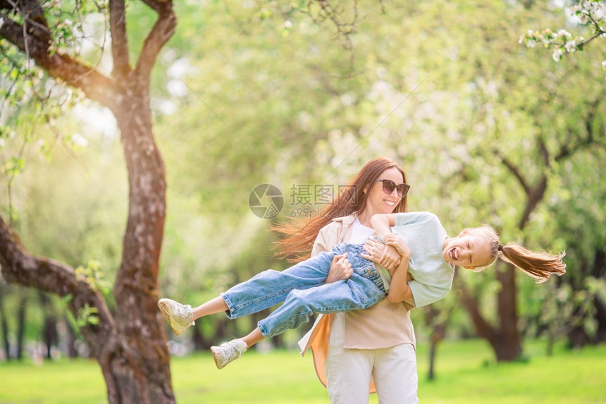 女孩分支母亲和儿的家庭在公园户外玩得开心在盛的樱花园中母亲和女儿家庭绿色图片
