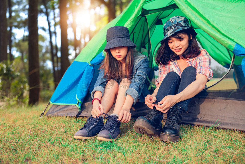 一群朋友观光旅游者在夏月露营时绑鞋带图片