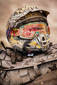 骑术竞赛摩托ATV和头盔被覆盖在泥土和中图片