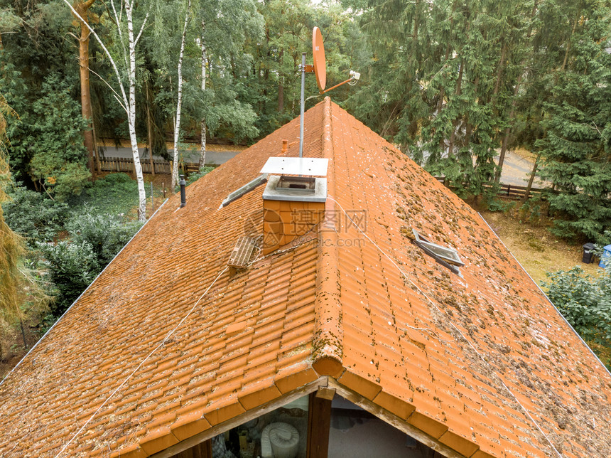 雨飞德国检查一个独立房屋的红色瓦式顶并装有覆盖烟囱和卫星天线图片
