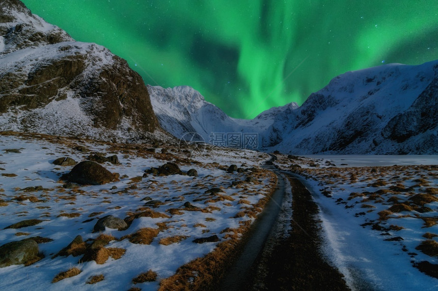 通向高山的美丽道路由北光或AuroraBorealis挪威冬季美丽的山地风景挪威斯堪的纳维亚冬季和挪威斯堪的纳维亚缰绳屋北极星图片