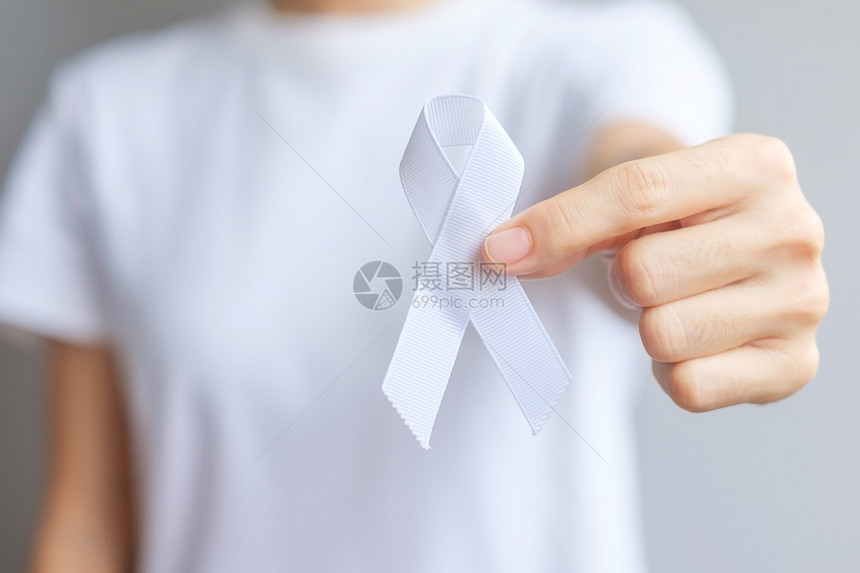 手捧白色丝带预防癌症概念图片