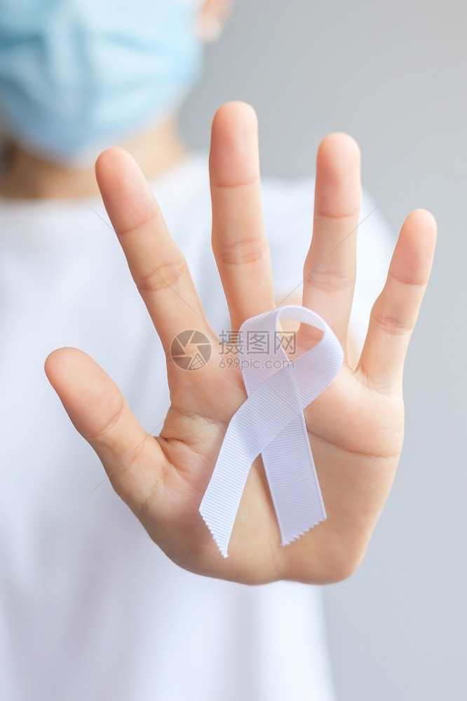 手拿白色丝带预防癌症概念特写图片
