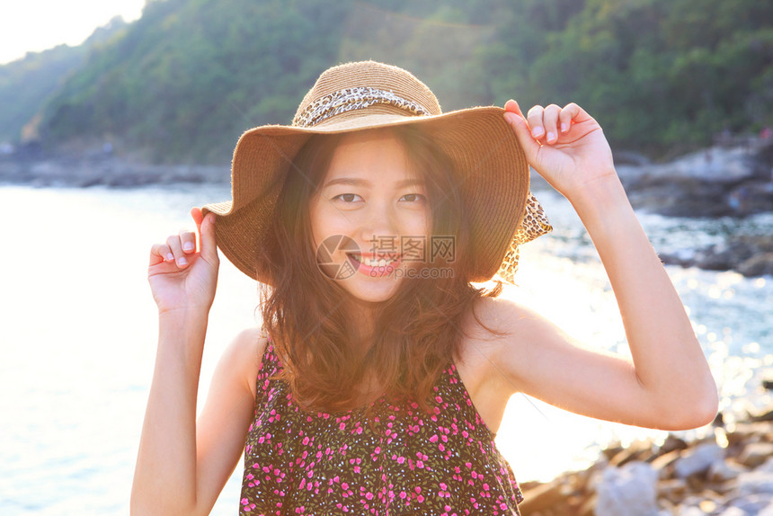 身戴宽草帽站在海边双眼仰望着摄影机供度假和青少年自然美人之用的丽女肖像画面并等待着他们用照相机拍摄年青少女的假期和自然美貌魅力成图片