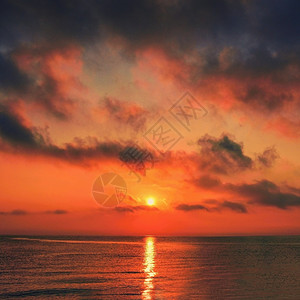海岸多云的暮美丽日出落在海滩的浪漫风景边夏天的概念图片